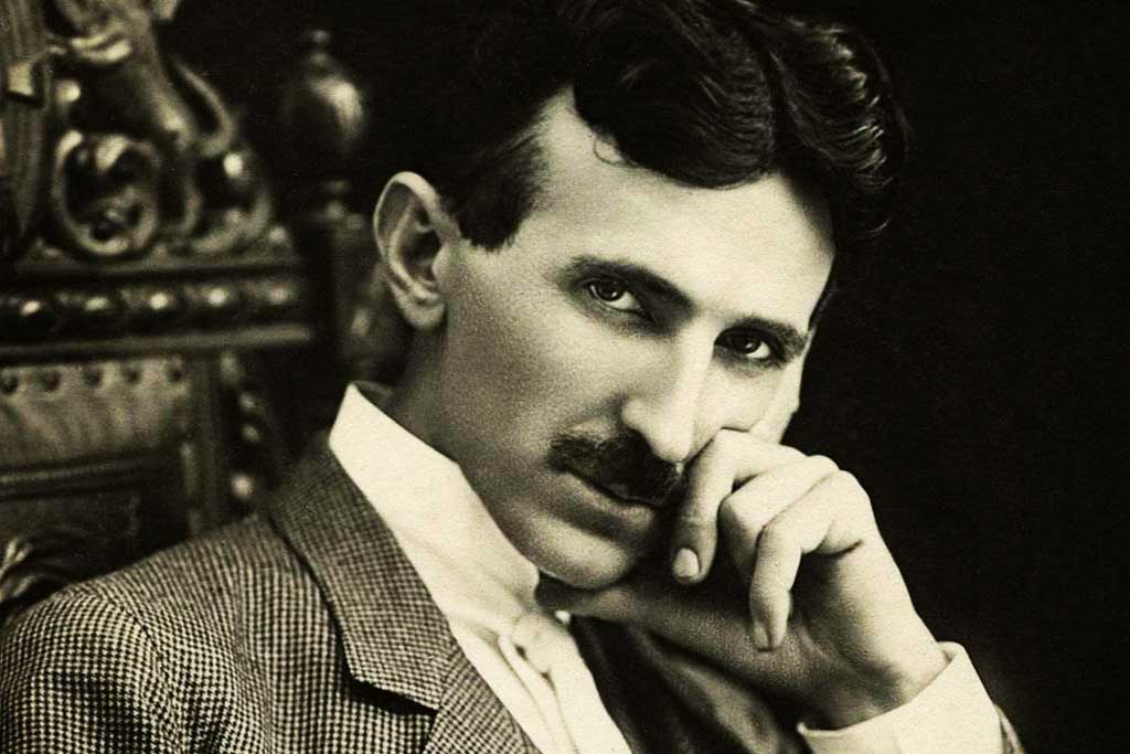 Retrato de Nikola Tesla olhando pensativamente para a câmera, com a mão apoiada no rosto.
